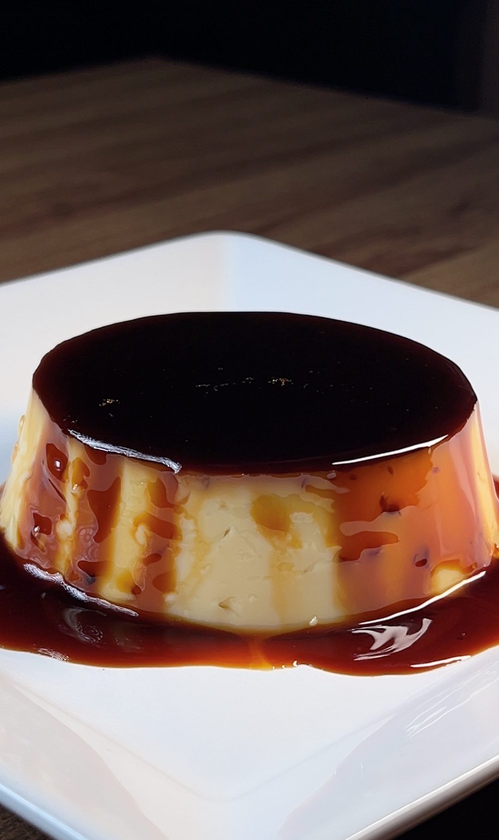 Pudim Premier Haus coberto com calda de caramelo, servido em prato branco