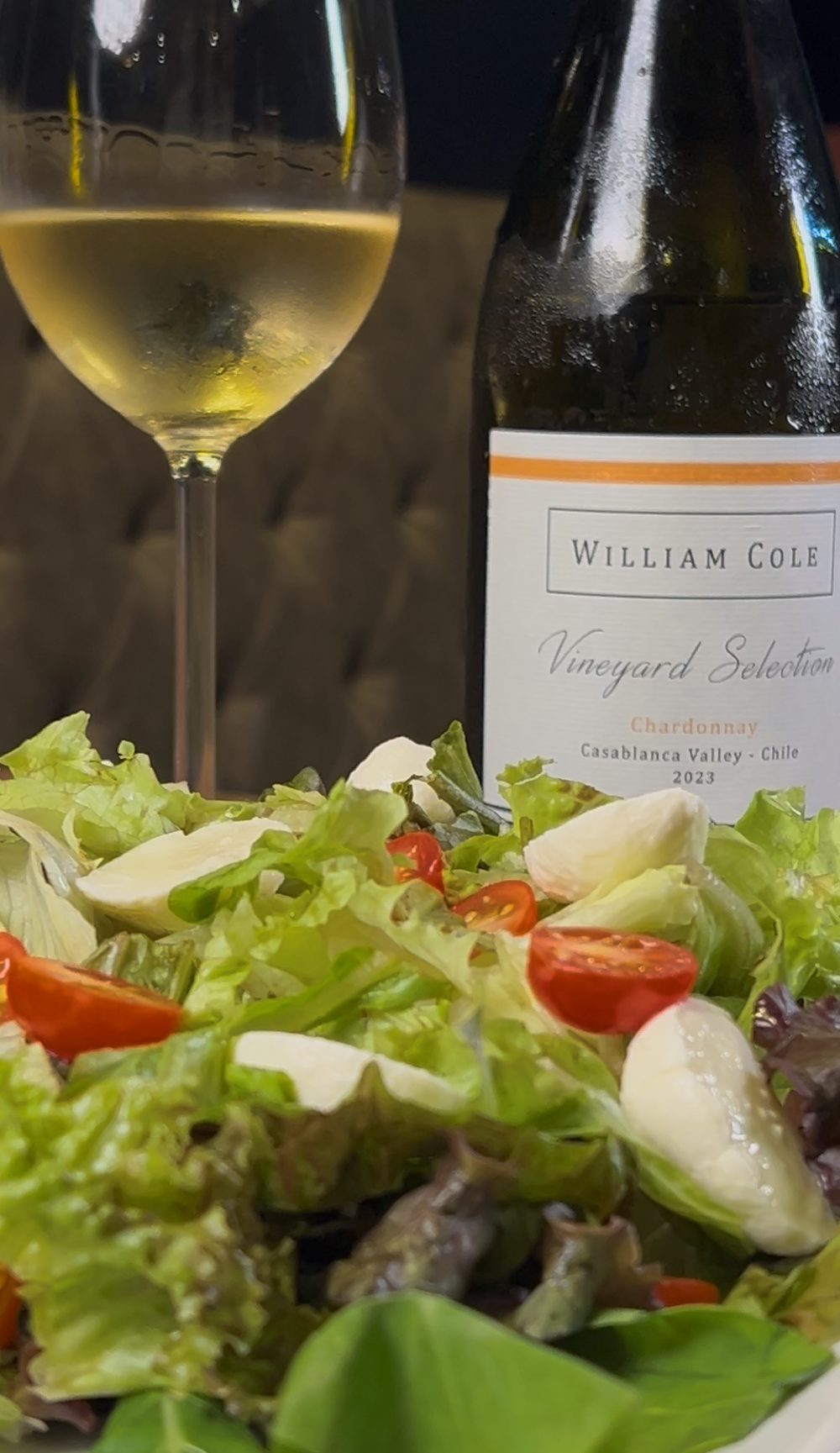 Salada Premier Haus servida ao lado da taça e da garrafa do vinho branco William Cole Chardonnay